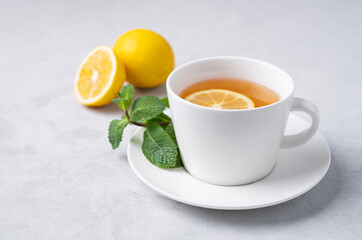 A cup of tea with lemon and mint on a light background. The concept of a healthy breakfast drink for  .immunity and vigor.