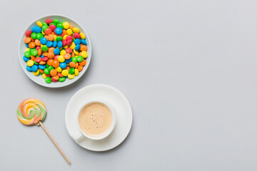Coffee cup with chocolates and colored candy. Top view on table background with copy space