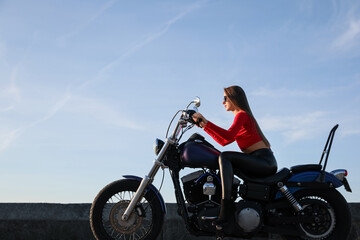 Beautiful young woman riding motorcycle on sunny day