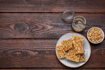 Fototapeta na wymiar Delicious peanut bars (kozinaki) and ingredients on wooden table, flat lay. Space for text