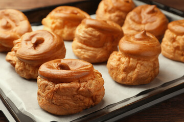 Delicious fresh profiteroles on baking pan, closeup