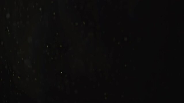 Snowflakes fly slowly in front of the camera. Snow illuminated at night by the light of a lantern. Recorded in slow motion.