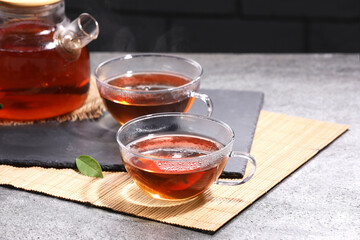 Aromatic hot tea in glass cups and teapot on light grey table