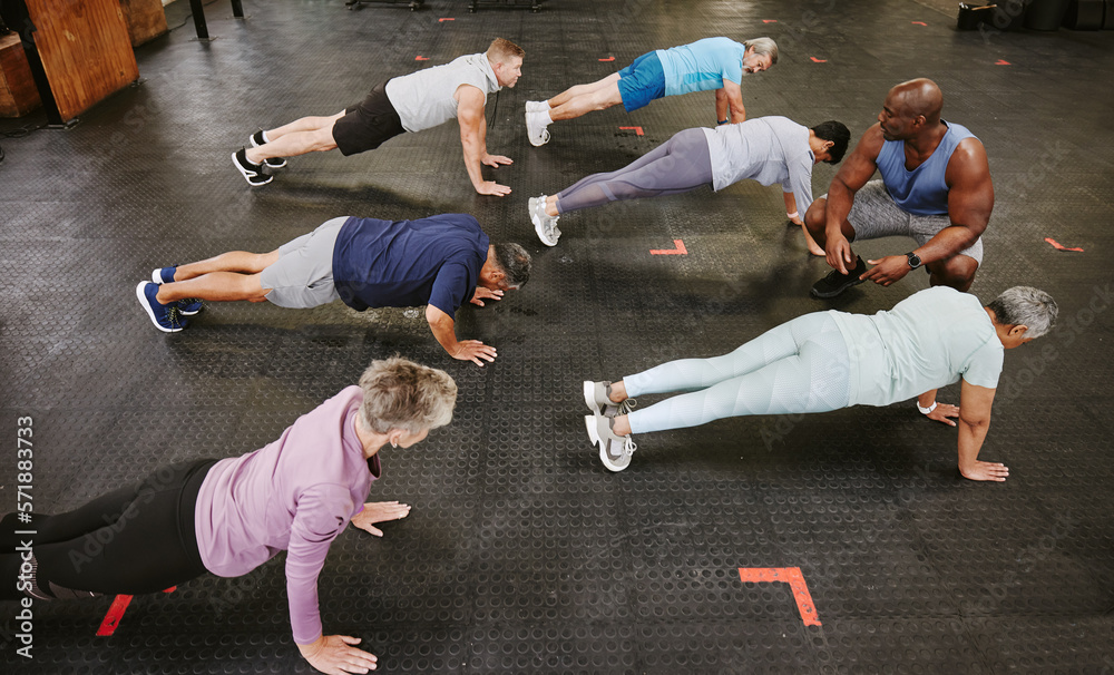 Wall mural People, fitness and stretching in class with personal trainer at gym for workout, exercise or training. Diverse group in warm up plank session with coach for healthy exercising or strong core muscles