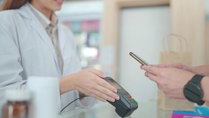 Fototapeta premium A customers buy medicines with pharmacists in drugstores and scan barcodes to payments