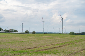 Wind park renewable energy wind turbines behind an agricultural field during cloudy day, mainz, germany