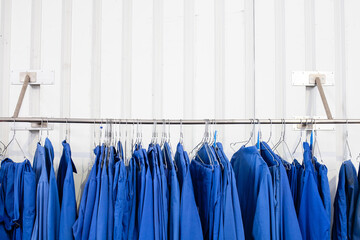 Blaue Arbeitskleidung, Blaumänner hängen auf einem Bügel an einer Stange