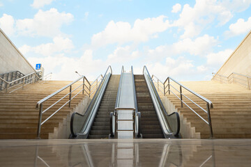 Stairs and escalator leading to blue sky with clouds