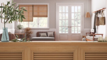 Fototapeta na wymiar Wooden table top, cabinet, panel or shelf with shutters close up. Olive branch in vase and candles. Blurred background, scandinavian living room with rattan sofa, interior design
