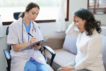 Obraz premium Portrait of a female doctor talking to an elderly patient showing headache.