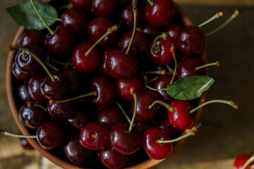 Cherries in a wooden bowl on a rustic background.