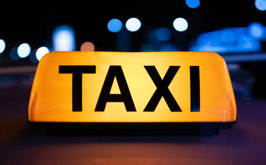 Taxi car yellow light sign on dark street at night with illumination. Cab service symbol with neon...