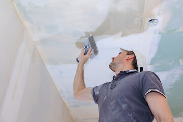 Worker make repairs in new apartment. Man plaster walls and ceilings. High quality photo