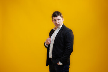 Portrait of focused businessman wearing suit standing on yellow studio background and looking at camera