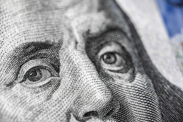 Close up macro view of one hundred dollars bill. Franklin eyes macro. The texture of the fragment of the dollar bill.
