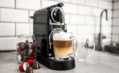 Coffee machine with capsules and creamy cappuccino in transparent cup at home. Espresso caffeine beverage maker and italian drink