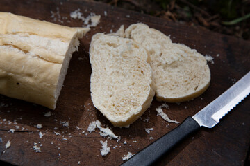 A piece of wheat bread for breakfast cut on a wooden board and a knife