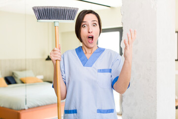 young pretty woman feeling extremely shocked and surprised. housekeeper concept