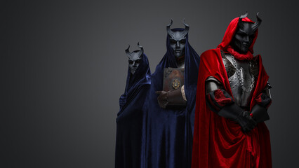 Portrait of dark cultists dressed in robes with hood and black horned masks.