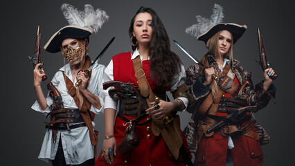 Portrait of carribean pirates women dressed in stylish costumes holding handguns.