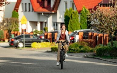 Cute laughing girl riding a bike in the evening in a calm city, back view. Eco-friendly urban transport.