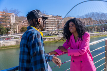 Young African American women in the city, friends lifestyle, talking and smiling by a river