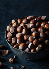 Hazelnut in a metal glass on a wooden background in rustic style. Raw hazelnuts. 