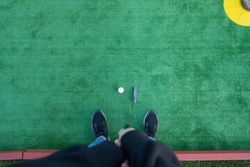 Top view of a unrecognizable golfer playing miniature golf