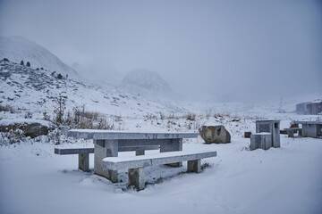 Winter landscape with snow-covered benches and misty mountains in Andorra