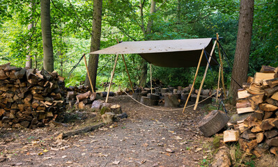 A woodpile and piles of logs at a forest resource preparation area for firewood fuel in UK woodland.