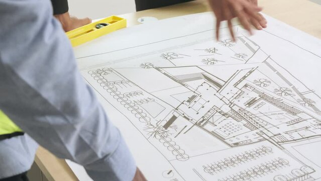 Hand of engineer and architect pointing to building construction design plans on blueprint at site.