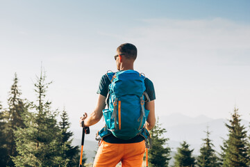 Hiker walking in mountains with poles on path in mountains at sunset. Lifestyle success concept adventure active vacations outdoor mountaineering sport