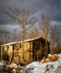 The sun setting on a building in Bainbridge in Upstate NY. An old abandoned building lit by the low sun on a Winter Evening makes for a nice warm photo. Tree and old building at sunset.