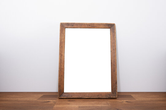rustic dark wood picture frame on a dark wood panel in front of a white wall as mock-up for designs with free plate plane