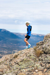 Young man practising trail running on a mountain top, copy space.