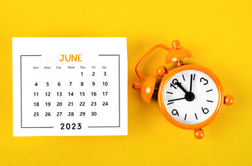 The June 2023 Monthly calendar for 2023 year with alarm clock on yellow background.