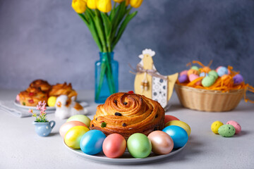 Fototapeta na wymiar Craffin (Cruffin) with raisins and candied fruits. Traditional Easter Bread Kulich and painted eggs on a gray background. Easter Holiday. Close-up, selective focus.