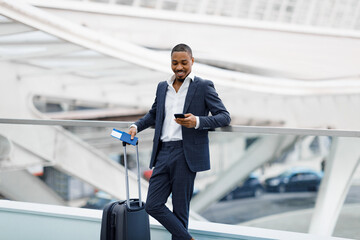 Smiling Black Businessman Using Smartphone While Waiting For Flight In Airport