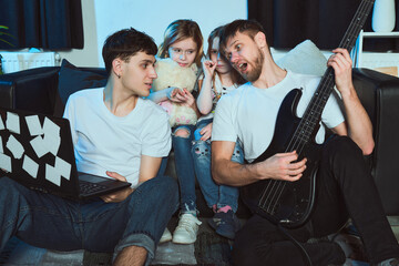 Staged photo. Homosexual couple and their children at home.  Saturday night. The whole family...