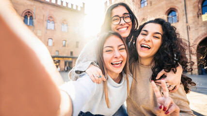 Three young women taking selfie picture with smart mobile phone on city street - Happy beautiful...