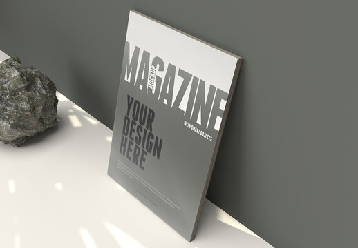Magazine Mockup on a Clean Army Green Wall With Leafs Shadows and a Rock on the Floor