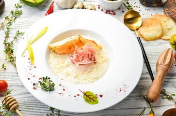 Cheese cream soup with prosciutto. Italian cuisine. Top view. Rustic style.