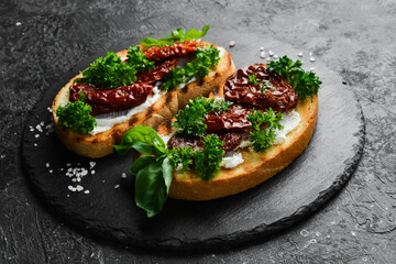 Sandwich with sun-dried tomatoes, cheese and basil. Bruschetta. Top view. On a stone background.