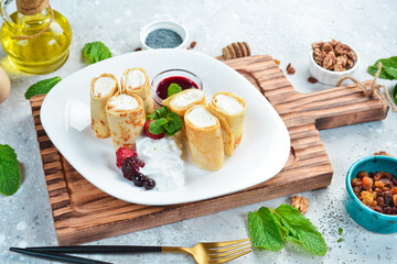 Dessert. Pancakes with cheese, berries and jam. On a white plate. On a gray stone background. Restaurant menu.