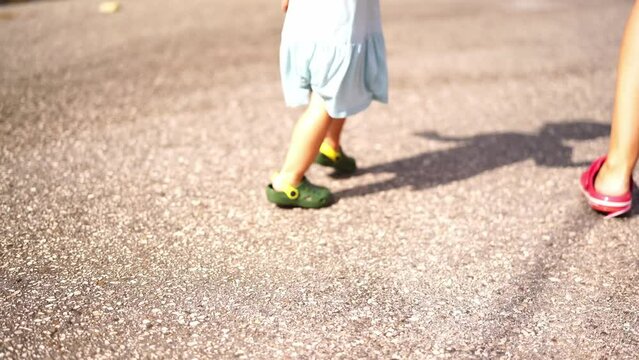 Little girl in flip-flops runs through the puddles on the road, raising splashes