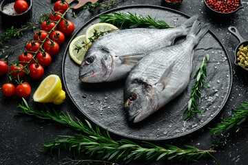 Fresh Dorado fish with spices is ready to cook. On a plate. On a black stone background.