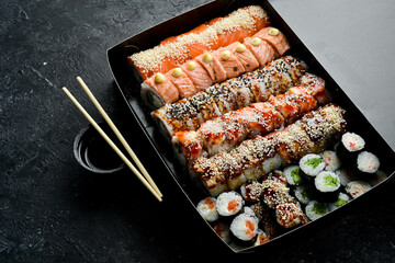 Sushi and rolls. Chinese food set. Takeout, food delivery. On a black stone background.