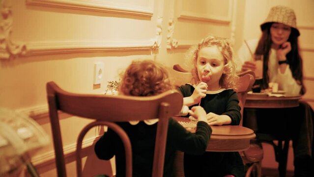 Woman and two little kids eating desserts in a small cafe