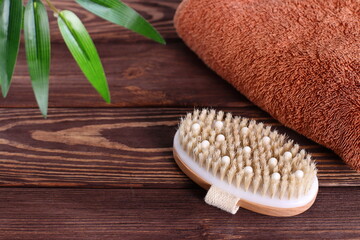 Brush for dry massage on wooden table with towel, lifestyle staging