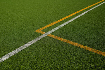 Sports field with green synthetic grass with a white and yellow line. Football, rugby, soccer,...